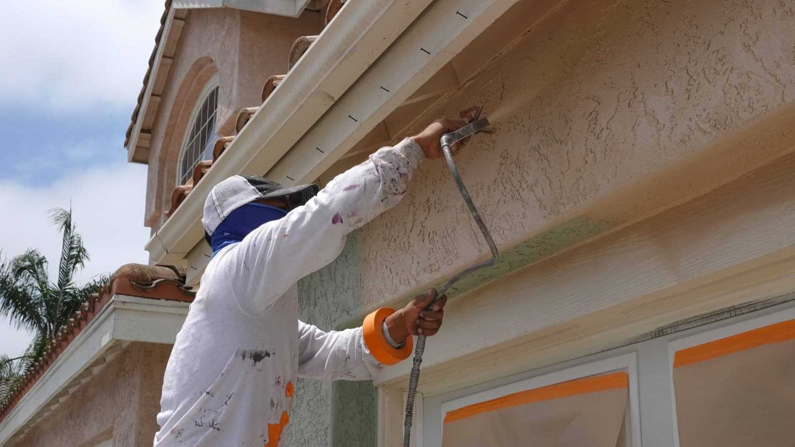 Painter spraying the exterior trim of a house