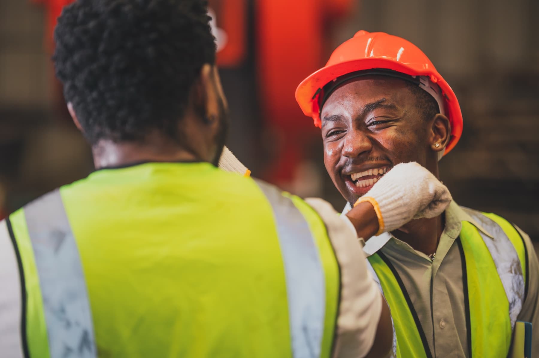 Two crew members in safety vests sharing a laugh on site
